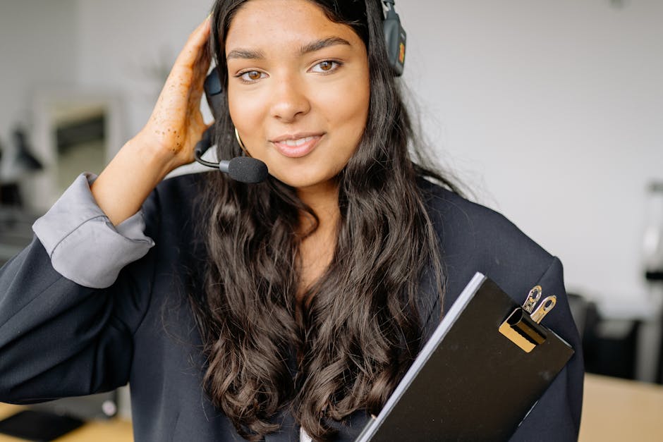 Smiling female call center representative with a headset in an office setting.